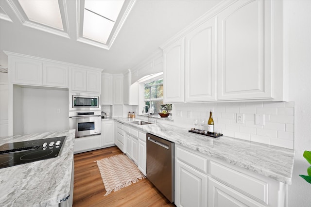 2949 Felstet Ln, Redding, CA 96001 - kitchen featuring appliances with stainless steel finishes, white cabinetry, tasteful backsplash, wood finished floors, and light stone countertops