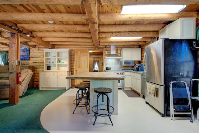 27401 Goodman Rd, Fall River Mills, CA 96028 - kitchen with a wooden ceiling with exposed beams, rustic walls, stainless steel appliances, white cabinets, and light colored carpet