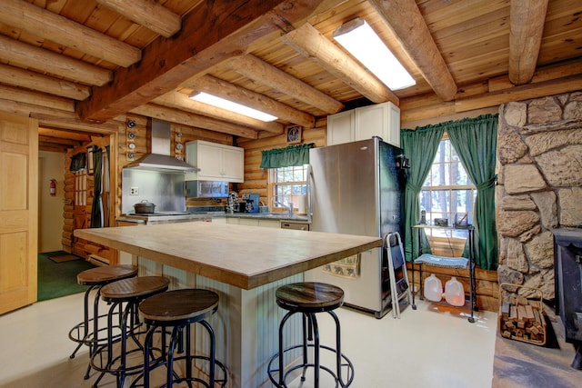 27401 Goodman Rd, Fall River Mills, CA 96028 - kitchen featuring a wooden ceiling with exposed beams, freestanding refrigerator, wall chimney range hood, white cabinetry, and finished concrete flooring
