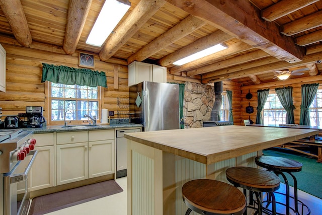 27401 Goodman Rd, Fall River Mills, CA 96028 - kitchen featuring rustic walls, a wood stove, a wooden ceiling with exposed beams, wood counters, and appliances with stainless steel finishes