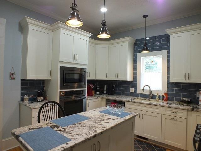 kitchen with decorative light fixtures, wall oven, tasteful backsplash, stainless steel microwave, and light stone counters