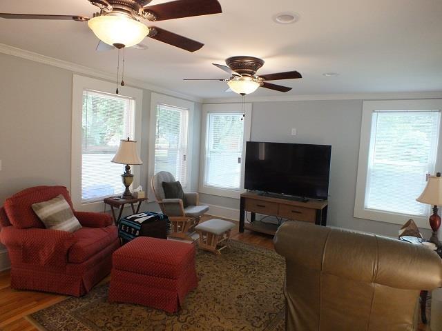 living room featuring hardwood / wood-style floors, ceiling fan, and crown molding