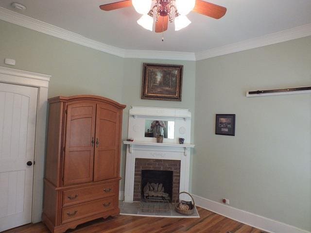 living room with ceiling fan, a brick fireplace, ornamental molding, and dark hardwood / wood-style floors