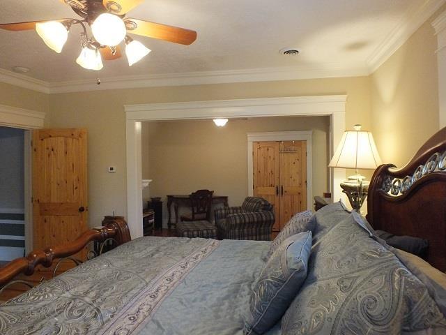 bedroom with ceiling fan and ornamental molding