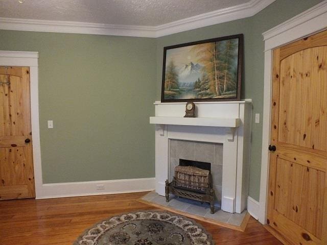 living room with a textured ceiling, a fireplace, ornamental molding, and light wood-type flooring