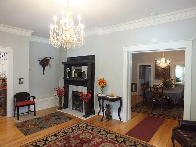 living room with light wood-type flooring, ornamental molding, and a chandelier