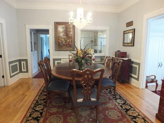 dining space featuring light hardwood / wood-style floors, ornamental molding, and a notable chandelier