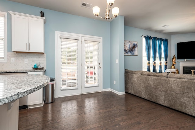 interior space featuring an inviting chandelier, dark wood-type flooring, tasteful backsplash, white cabinets, and pendant lighting