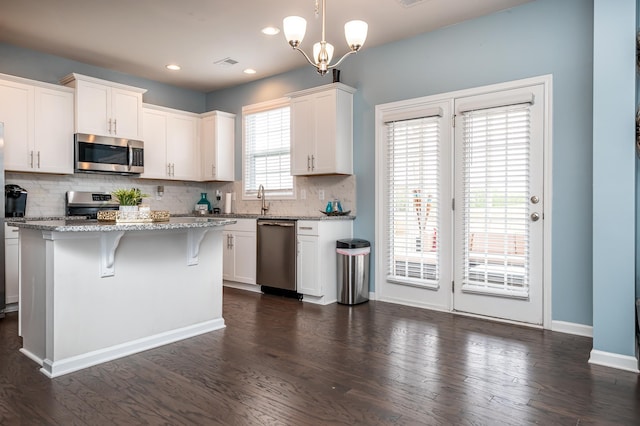 kitchen featuring a chandelier, hanging light fixtures, stainless steel appliances, and dark hardwood / wood-style flooring