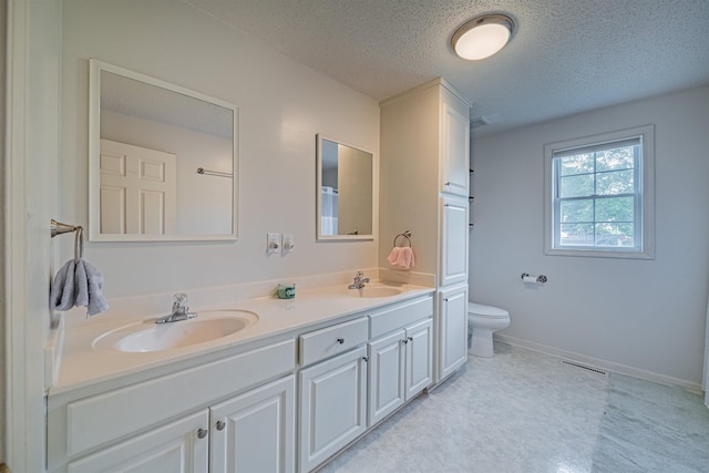 bathroom with toilet, large vanity, double sink, a textured ceiling, and tile flooring