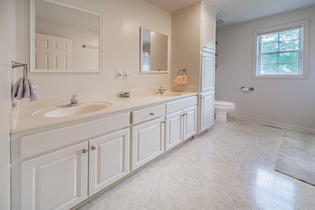 bathroom featuring toilet, a textured ceiling, double sink, and large vanity