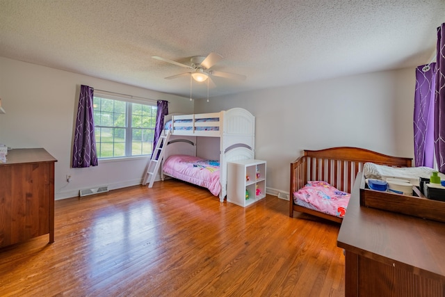 bedroom featuring light hardwood / wood-style floors, a textured ceiling, and ceiling fan