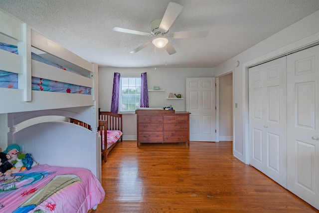 bedroom featuring dark hardwood / wood-style flooring, ceiling fan, a textured ceiling, and a closet