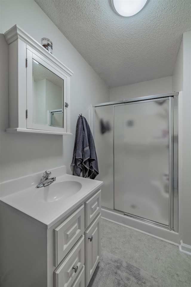 bathroom featuring a shower with shower door, a textured ceiling, and vanity