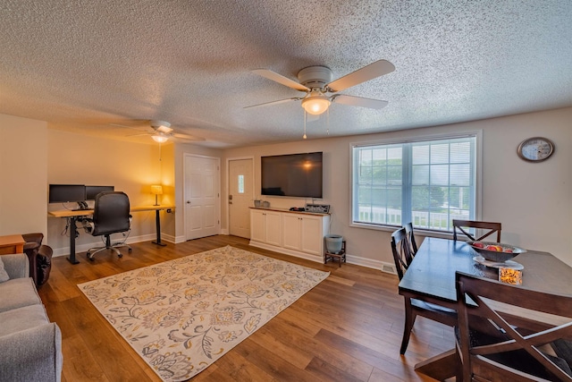 living room featuring ceiling fan, dark wood-type flooring, and a textured ceiling