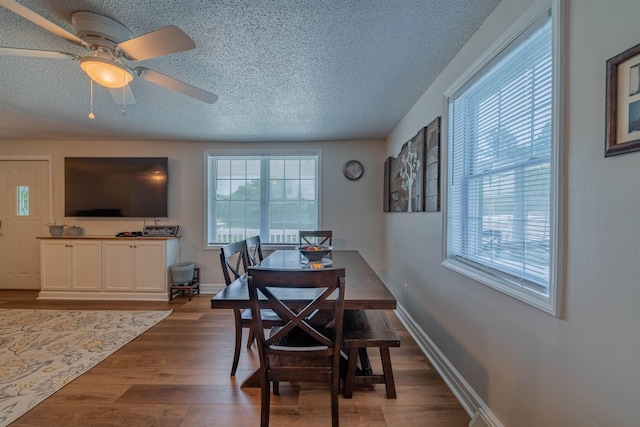 dining room with a textured ceiling, wood-type flooring, and ceiling fan