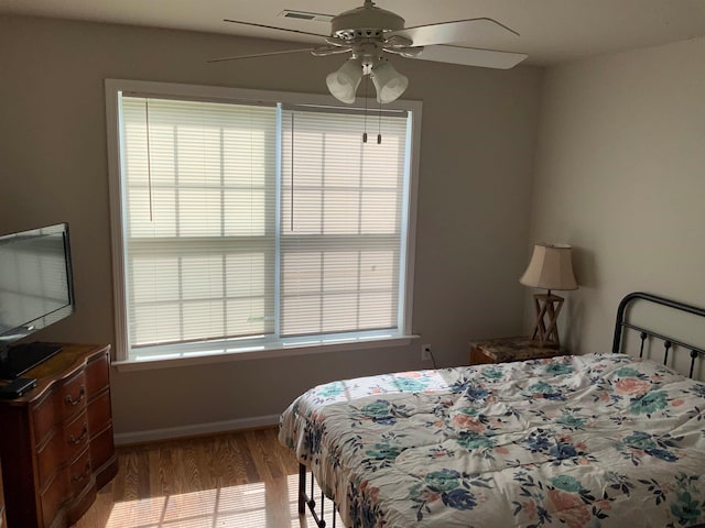 bedroom with wood-type flooring, ceiling fan, and multiple windows