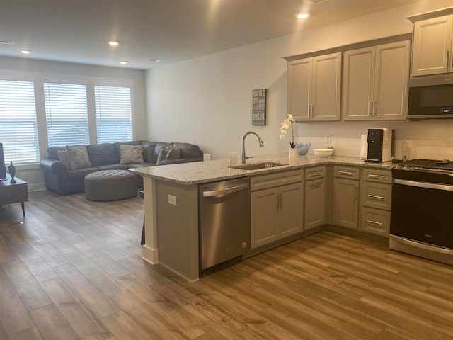 kitchen featuring sink, light stone counters, stainless steel appliances, dark wood-type flooring, and tasteful backsplash