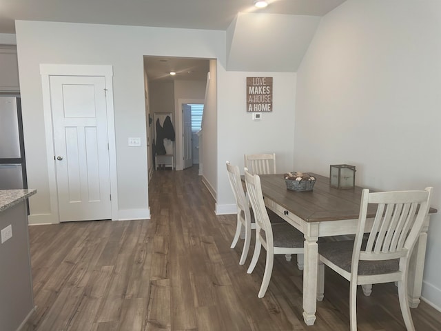 dining space featuring lofted ceiling and dark wood-type flooring