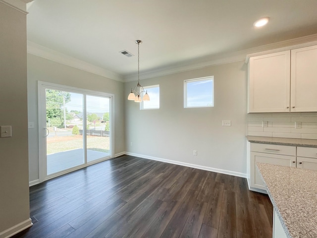 unfurnished dining area with ornamental molding, a healthy amount of sunlight, dark hardwood / wood-style floors, and a chandelier