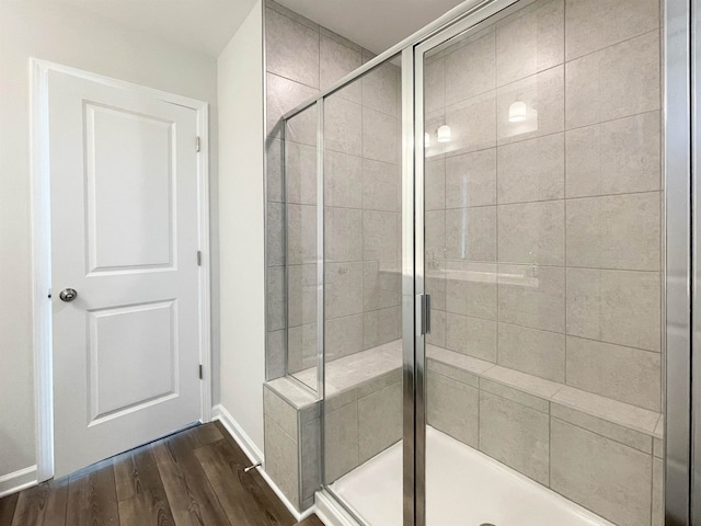 bathroom with hardwood / wood-style floors and a shower with shower door