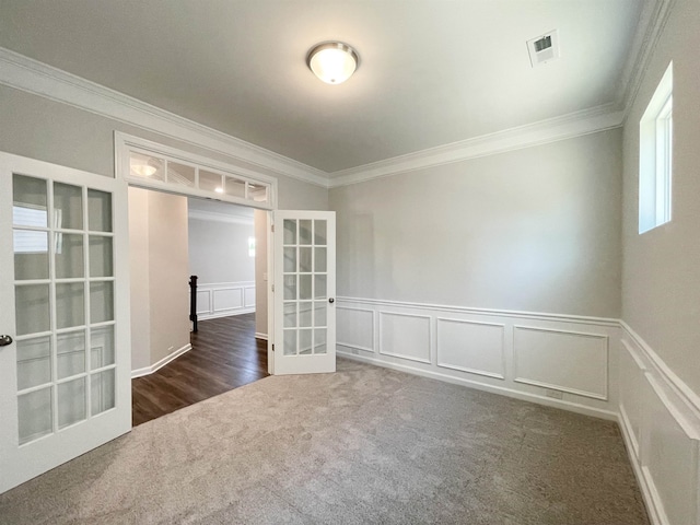 unfurnished room featuring dark colored carpet, crown molding, and french doors