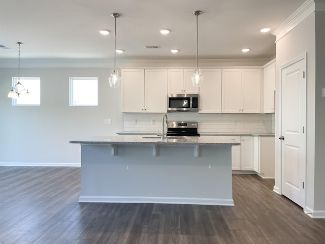 kitchen featuring stainless steel appliances, decorative light fixtures, an island with sink, and white cabinets