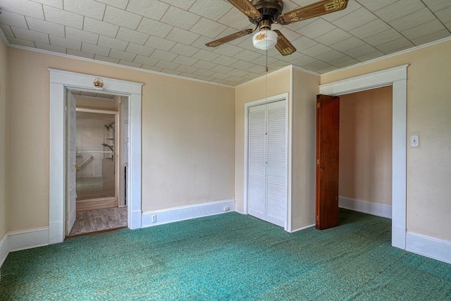 unfurnished bedroom featuring ornamental molding, ceiling fan, a closet, and dark colored carpet