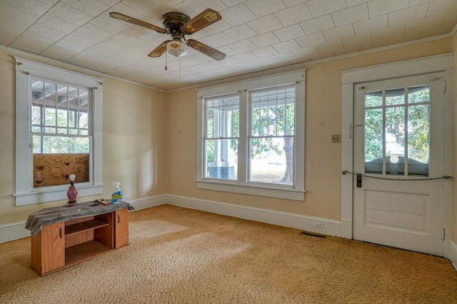 interior space featuring light colored carpet, crown molding, ceiling fan, and a wealth of natural light