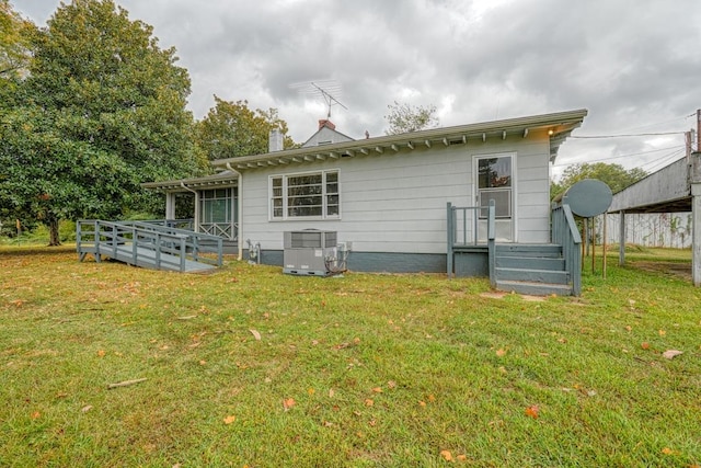 rear view of property featuring central air condition unit, a wooden deck, and a lawn