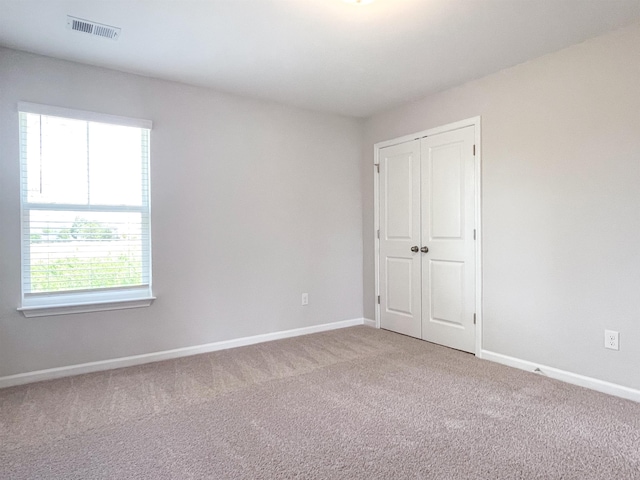 unfurnished bedroom with a closet, carpet floors, and multiple windows