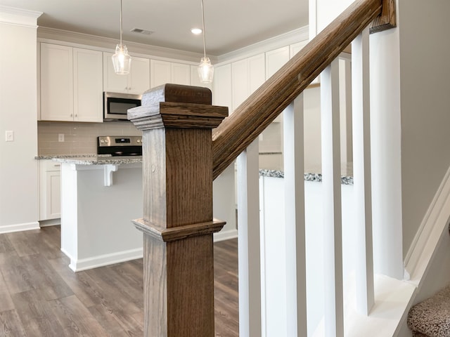 kitchen with pendant lighting, backsplash, range, light stone countertops, and dark wood-type flooring