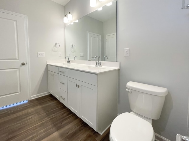 bathroom featuring dual sinks, toilet, hardwood / wood-style floors, and vanity with extensive cabinet space