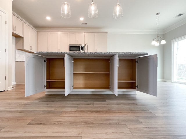 kitchen featuring an inviting chandelier, light stone countertops, crown molding, and light wood-type flooring