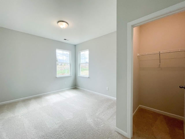 unfurnished bedroom with a closet, a spacious closet, and light colored carpet