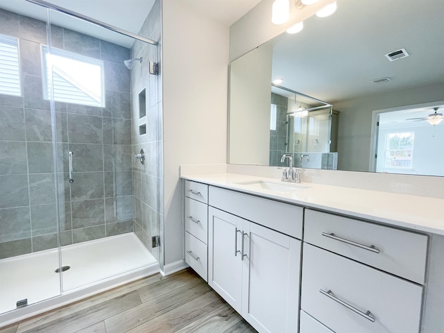 bathroom with vanity, a shower with door, ceiling fan, and wood-type flooring