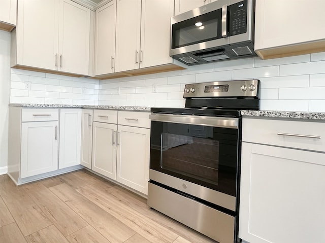 kitchen with tasteful backsplash, stainless steel appliances, and light wood-type flooring