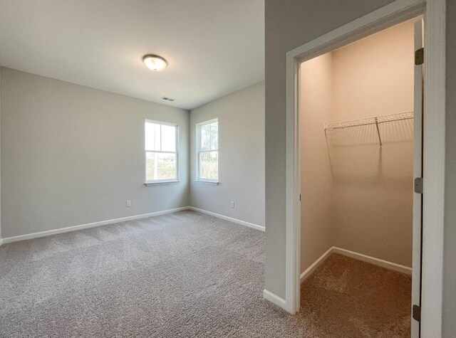 unfurnished bedroom featuring a walk in closet, carpet flooring, and a closet