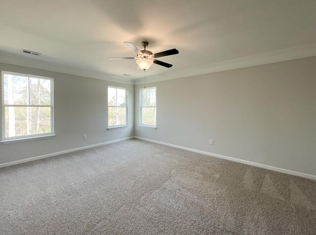 carpeted spare room with crown molding, ceiling fan, and a healthy amount of sunlight