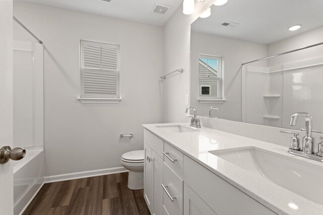 bathroom featuring toilet, wood finished floors, visible vents, and a sink