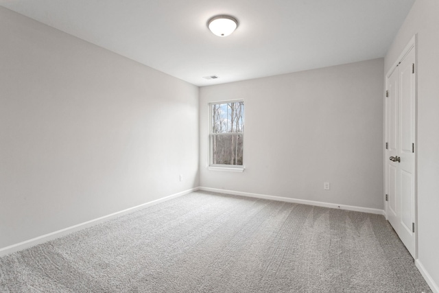 spare room with visible vents, carpet, and baseboards