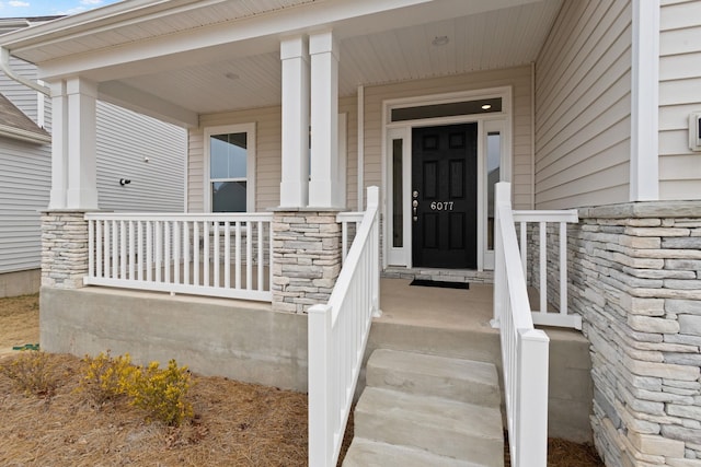 view of exterior entry featuring a porch and stone siding