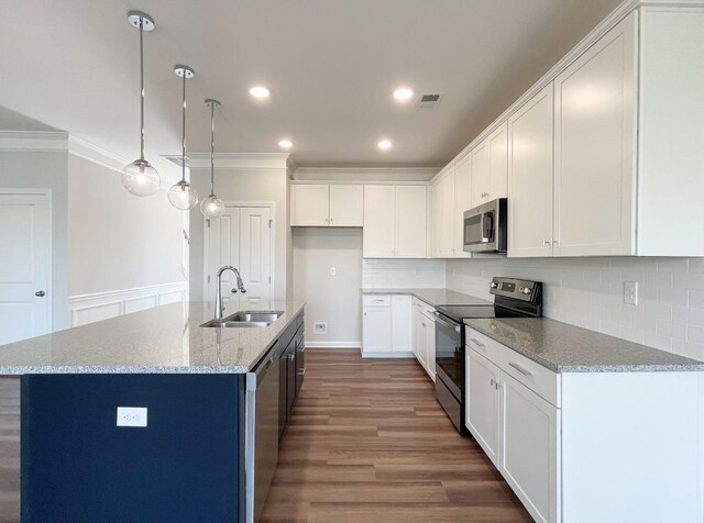 kitchen featuring appliances with stainless steel finishes, sink, white cabinets, hanging light fixtures, and a kitchen island with sink