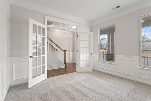 empty room with visible vents, french doors, carpet floors, stairway, and crown molding