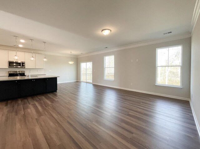 unfurnished living room featuring ornamental molding, dark wood-type flooring, and a wealth of natural light