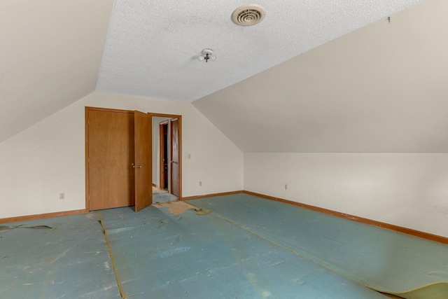 additional living space featuring lofted ceiling and a textured ceiling