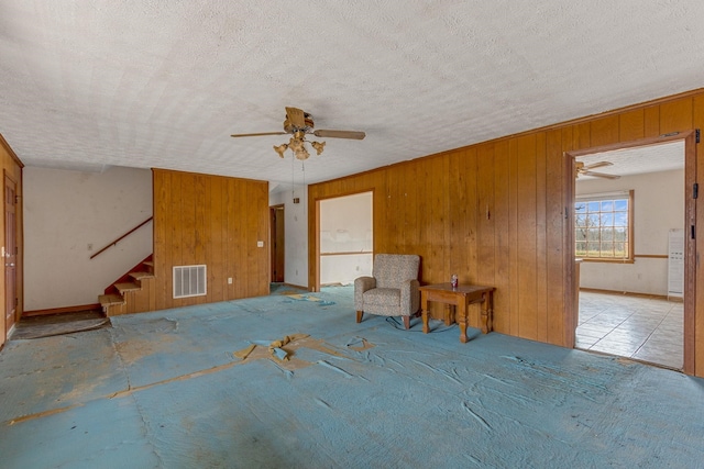 interior space featuring wood walls, a textured ceiling, and ceiling fan