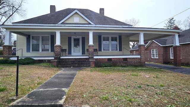 bungalow-style home with a front yard and covered porch