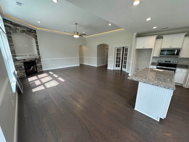 kitchen featuring dark wood-type flooring, appliances with stainless steel finishes, a fireplace, and ornamental molding