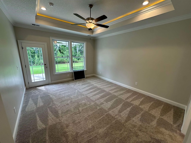 empty room with crown molding, ceiling fan, a raised ceiling, and carpet flooring